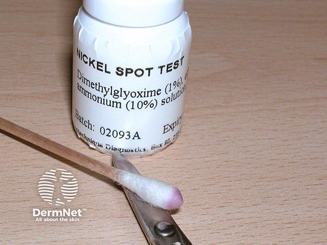 Dimethylglyoxime (DMG) - one drop on a cotton bud is rubbed over a metal item. The reddish-purple colour indicates nickel content